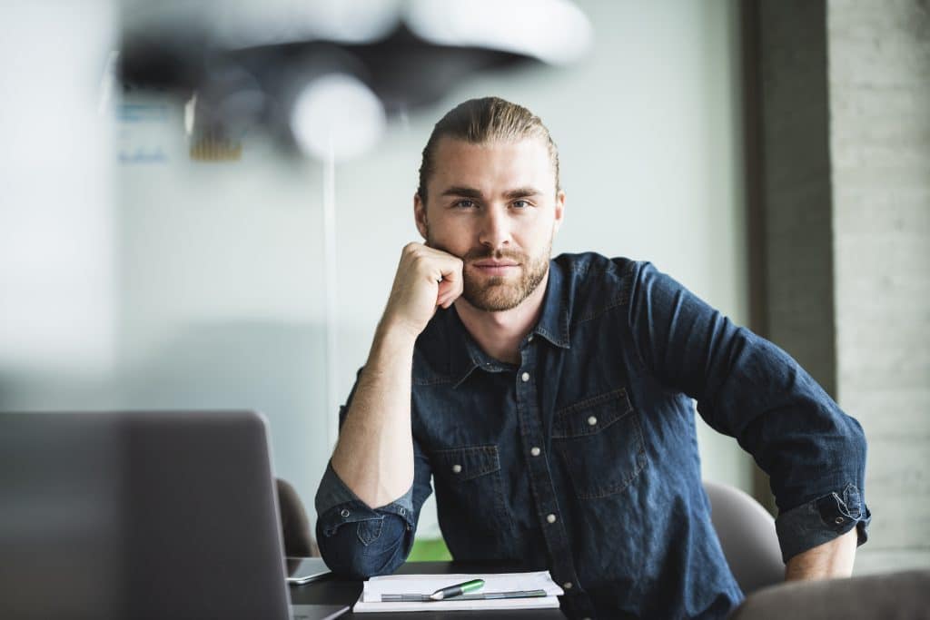 Confident casual businessman sitting at a desk in his office
